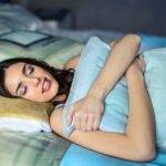 A woman sleeping peacefully in bed hugging a Hypoallergenic Pillows, evoking comfort and relaxation.