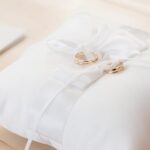 Gold wedding rings elegantly displayed on a white satin pillow, symbolizing love and commitment.